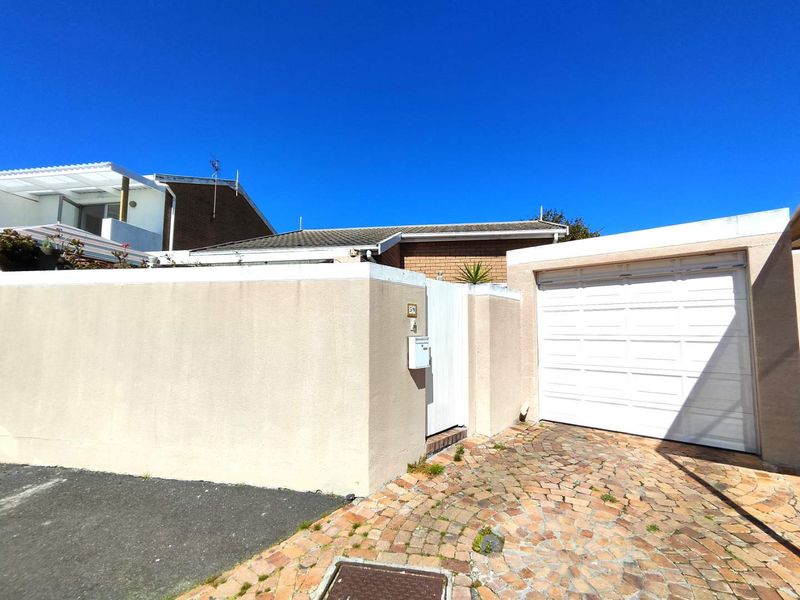 Front exterior view of the property featuring a single garage, gated pedestrian entrance, and a cobblestone driveway.