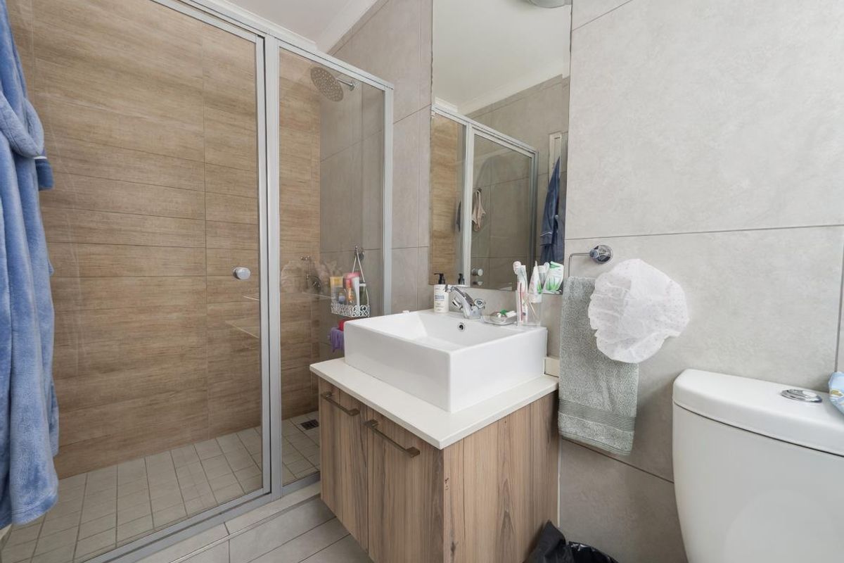Modern bathroom featuring a walk-in shower with wood-look tiling, a floating vanity with a vessel sink, and a wall-mounted mirror.