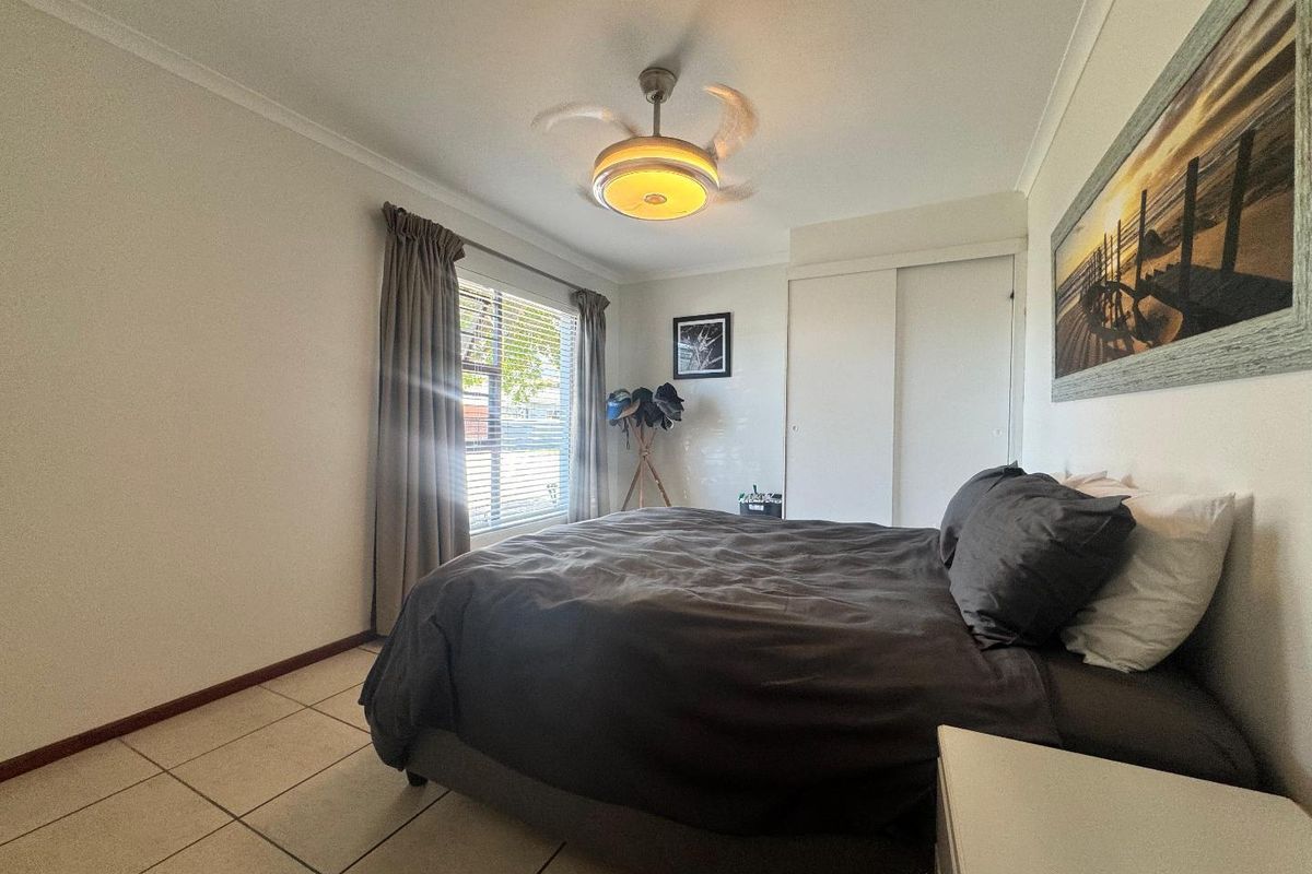 A bedroom featuring tiled flooring, a built-in wardrobe, and a ceiling fan, offering a functional and well-lit space.