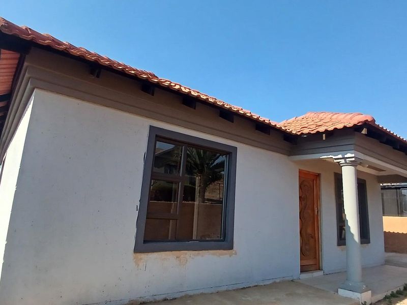 A single-story residential house featuring a terracotta tiled roof, a covered front porch with concrete columns, and modern aluminium window frames.