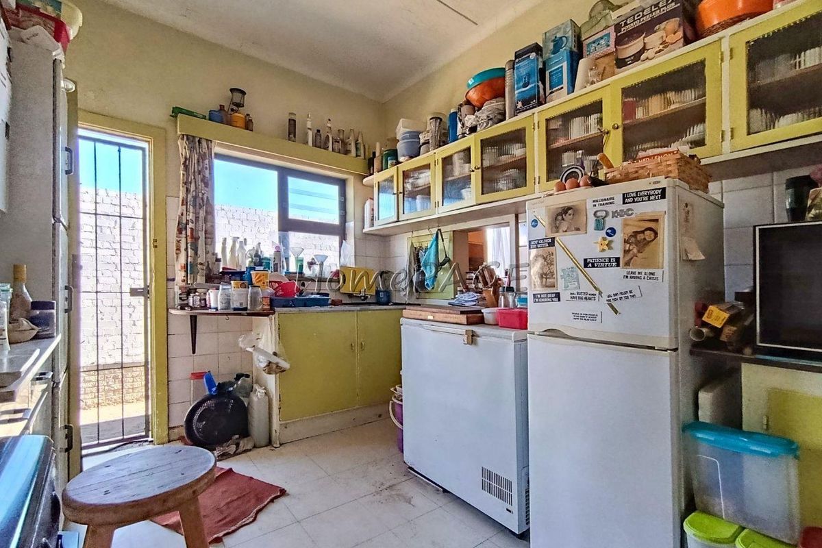 A dated kitchen featuring built-in cabinetry, tiled flooring, and direct access to an exterior area, offering potential for a modern renovation.