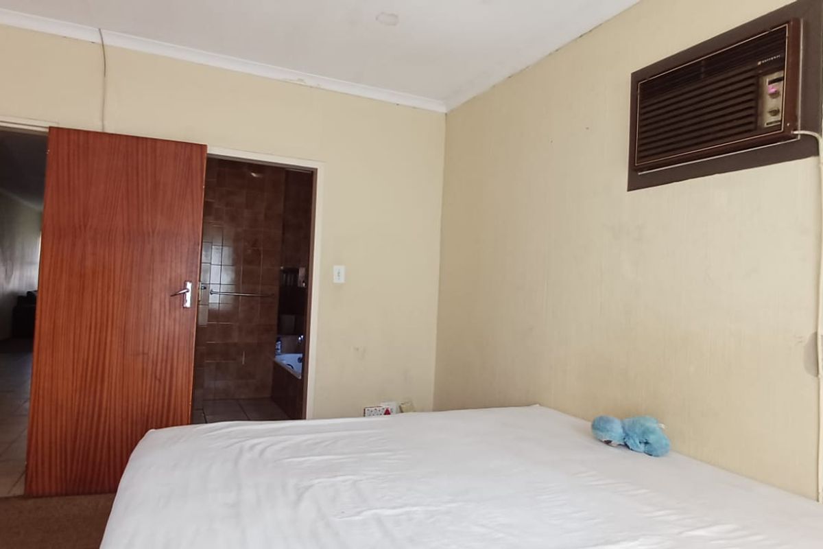 Bedroom featuring a wall-mounted air conditioning unit and direct access to an en-suite bathroom with tiled finishes.