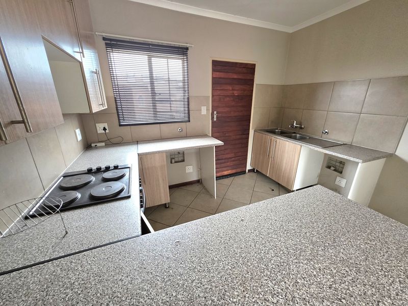 Functional kitchen featuring laminate cabinetry, granite-look countertops, an electric hob, and a double bowl sink, ready for modern updates.
