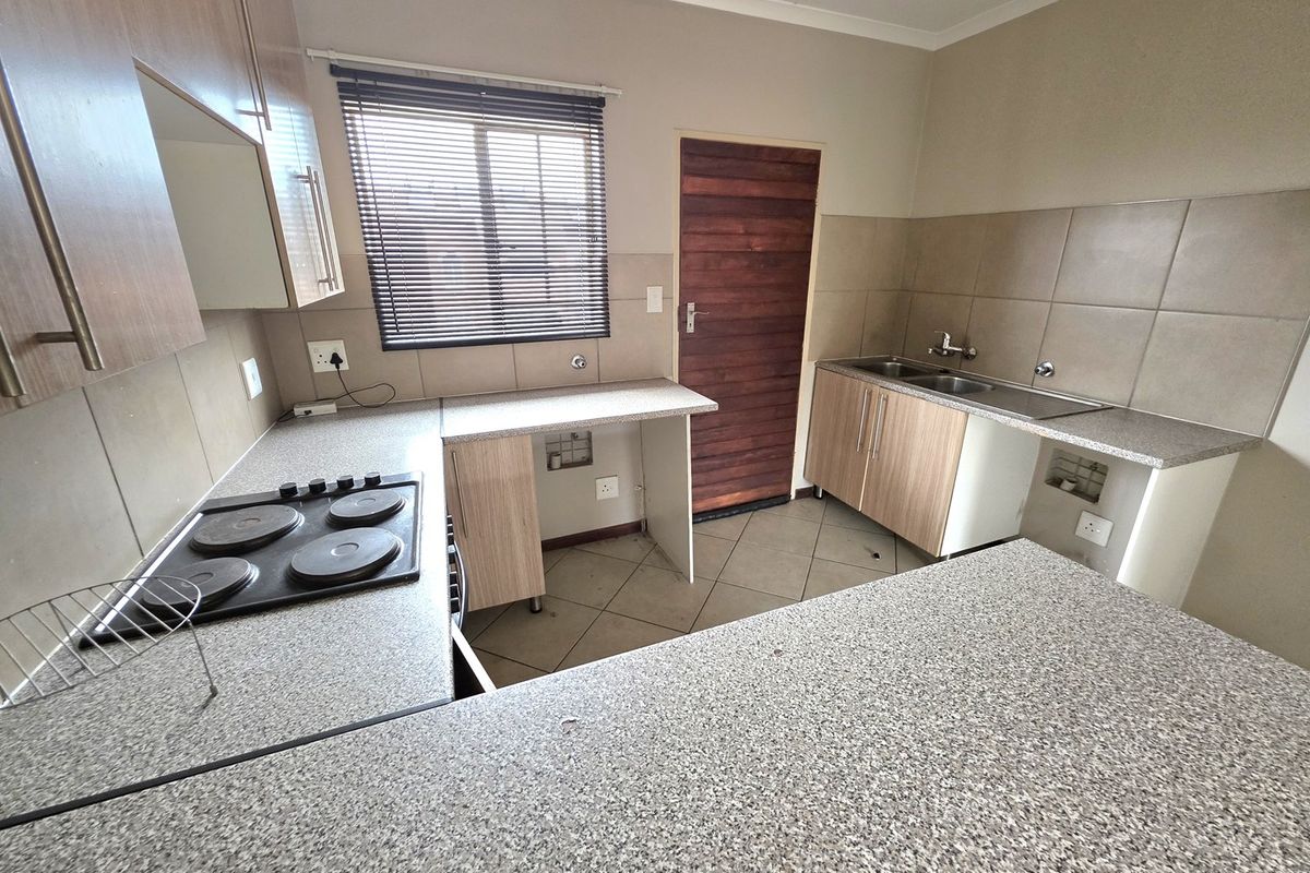 Functional kitchen featuring laminate cabinetry, granite-look countertops, an electric hob, and a double bowl sink, ready for modern updates.