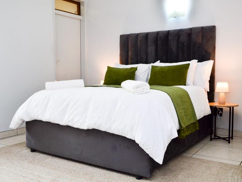 A well-maintained bedroom featuring tiled flooring and a wall-mounted light fixture, providing a clean and functional sleeping space.