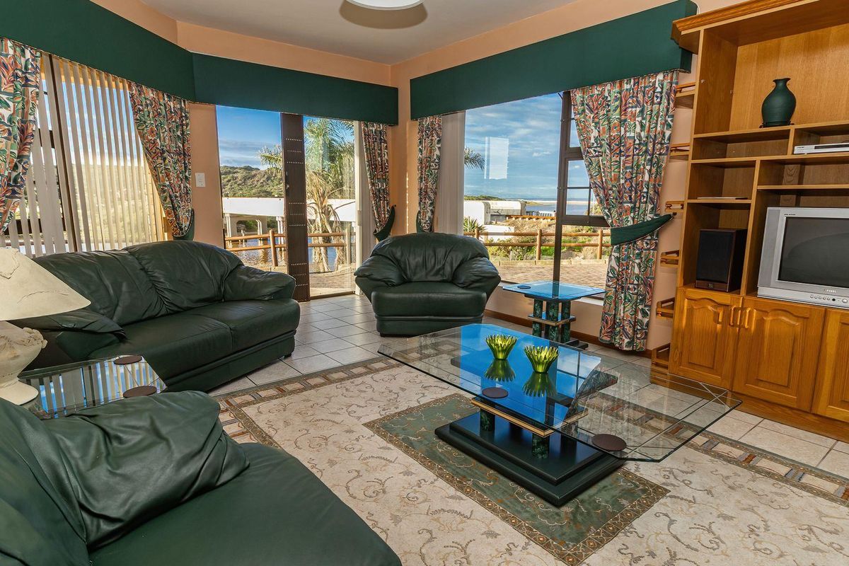 Spacious living room featuring large windows with scenic views, tiled flooring, and built-in wooden cabinetry.