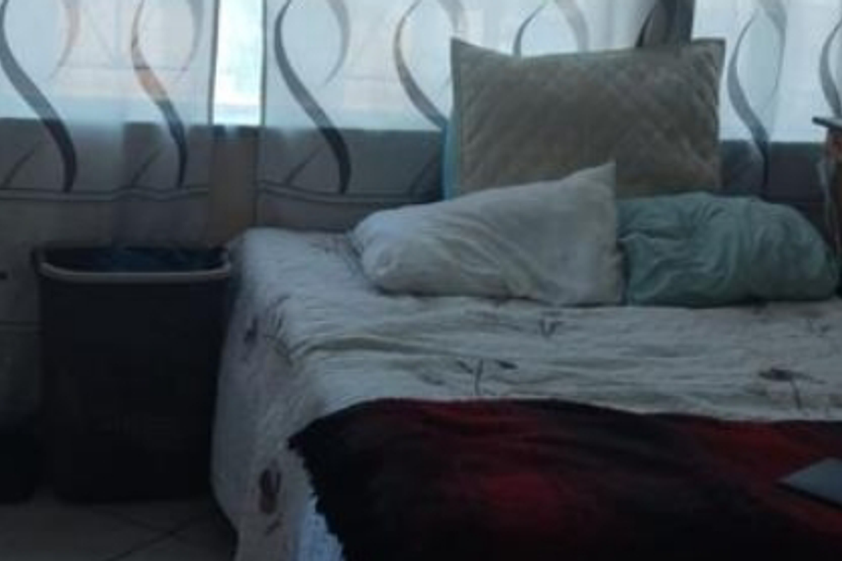 A bedroom featuring tiled flooring and large windows with curtains, providing natural light to the space.
