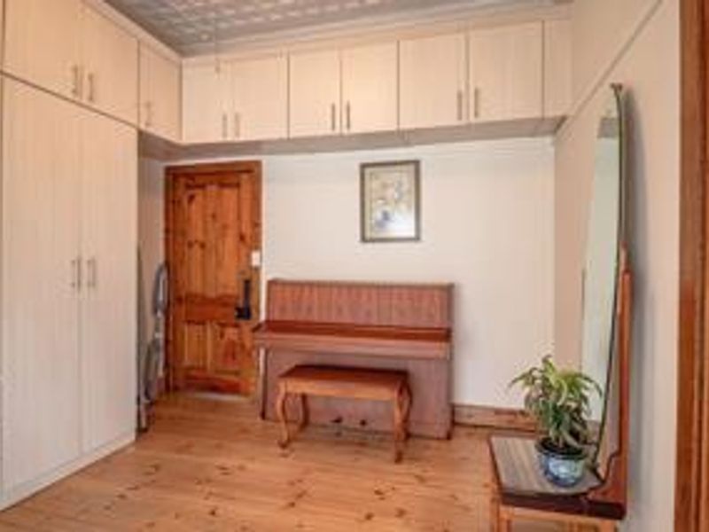 Bedroom featuring extensive built-in cabinetry, warm timber flooring, and a classic pressed metal ceiling, offering ample storage and a traditional aesthetic.