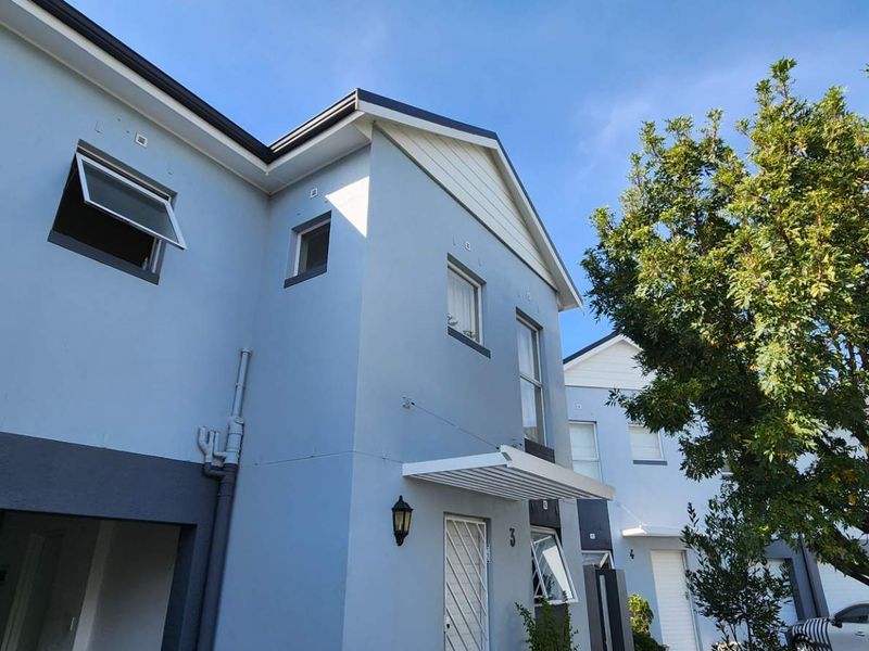 Front elevation of a two-story townhouse featuring a light blue painted facade, modern awning, and secure entrance.