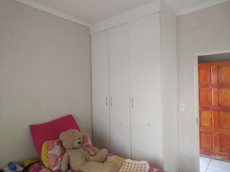 A bedroom featuring a white built-in wardrobe with ample storage space.