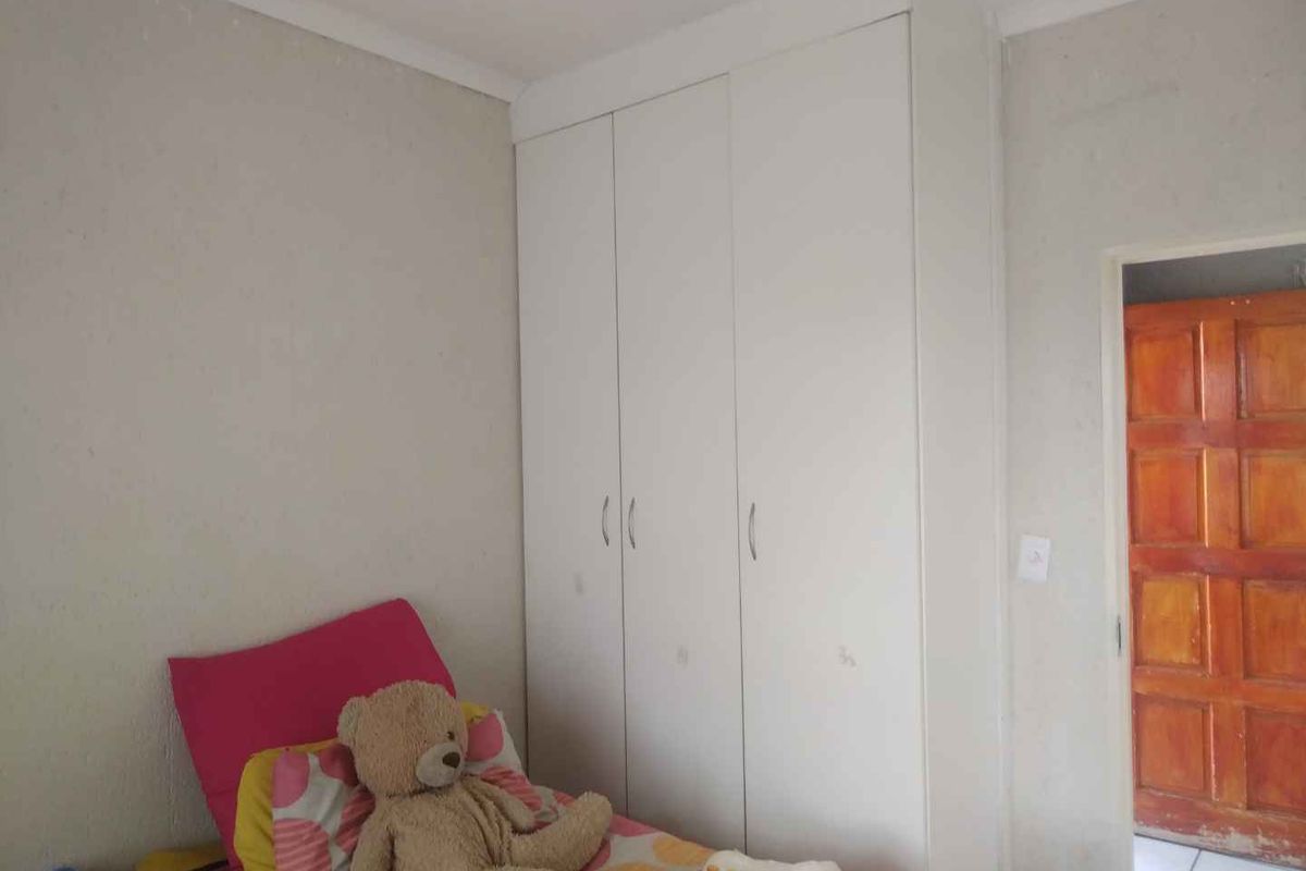 A bedroom featuring a white built-in wardrobe with ample storage space.