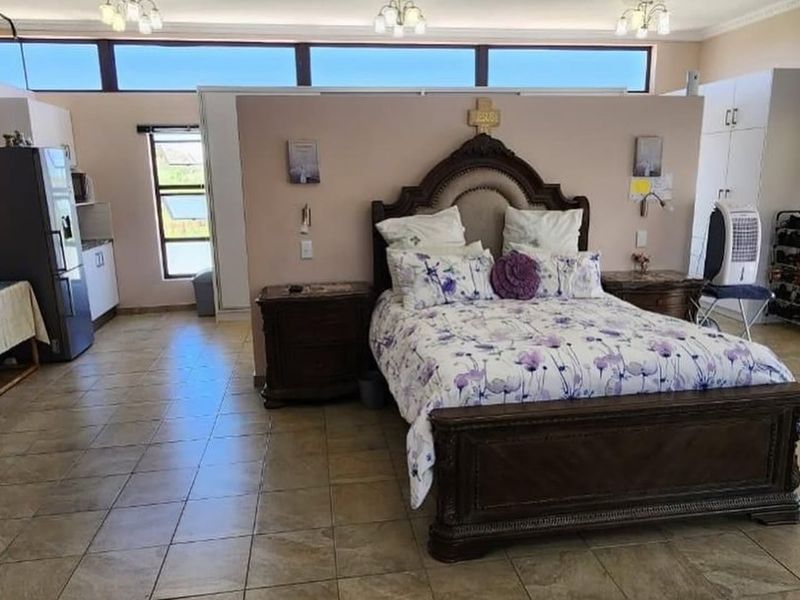 An open-plan bedroom and kitchen area featuring tiled flooring, built-in storage, and high-level clerestory windows providing natural light.