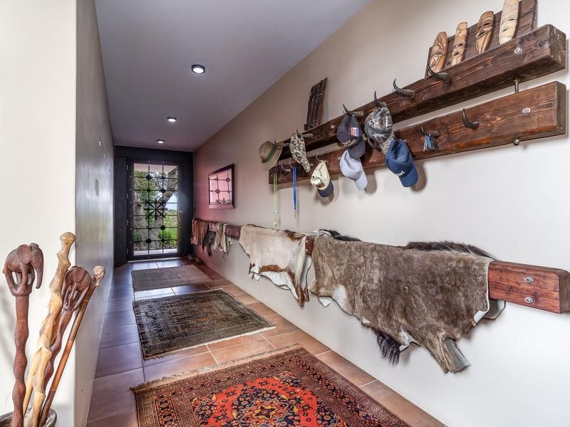 A spacious hallway featuring tiled flooring, recessed downlighting, and a secure metal entrance door.