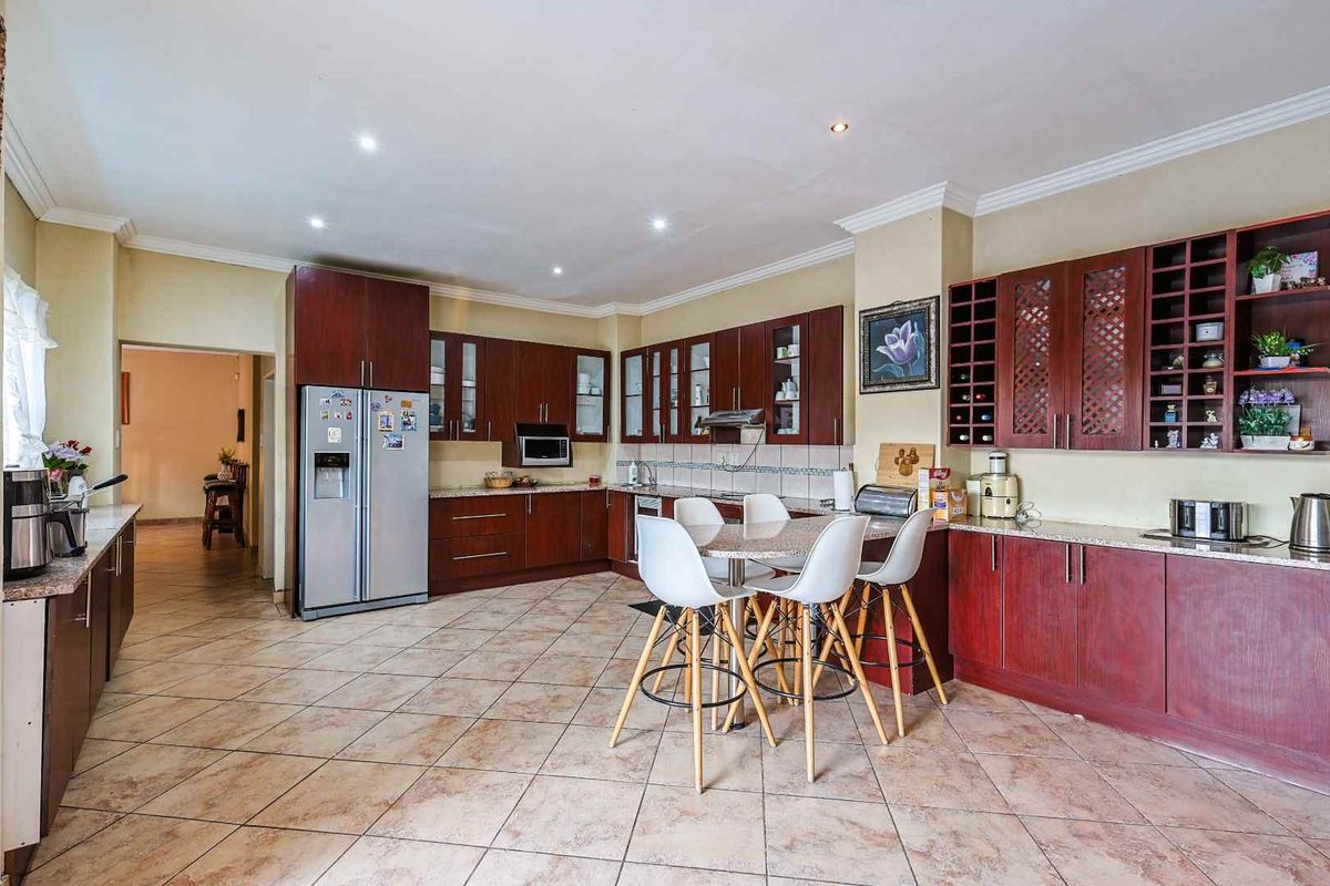 Spacious kitchen featuring dark wood cabinetry, granite countertops, tiled flooring, and a built-in breakfast bar area with recessed lighting.