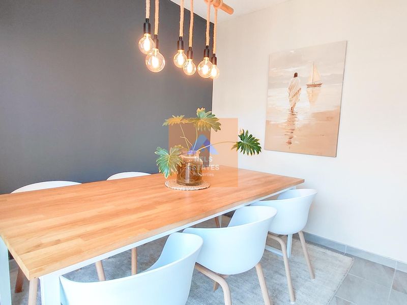 A bright dining area featuring modern pendant lighting and neutral tiled flooring, creating a clean and inviting space for meals.