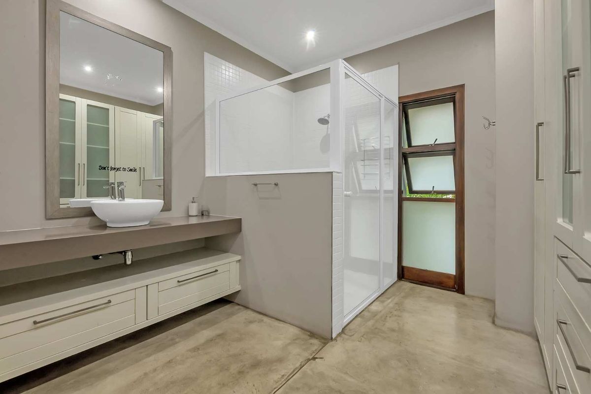 Modern bathroom featuring a vessel sink on a floating vanity, a walk-in shower with white tiling, and polished concrete flooring.