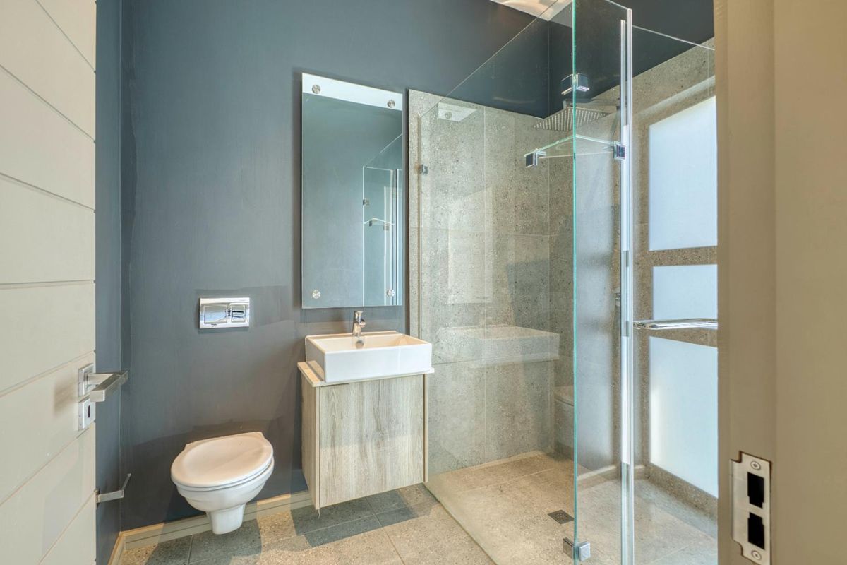 Modern bathroom featuring a floating vanity, vessel sink, wall-mounted toilet, and a spacious walk-in shower with glass enclosure and stone-look tiling.