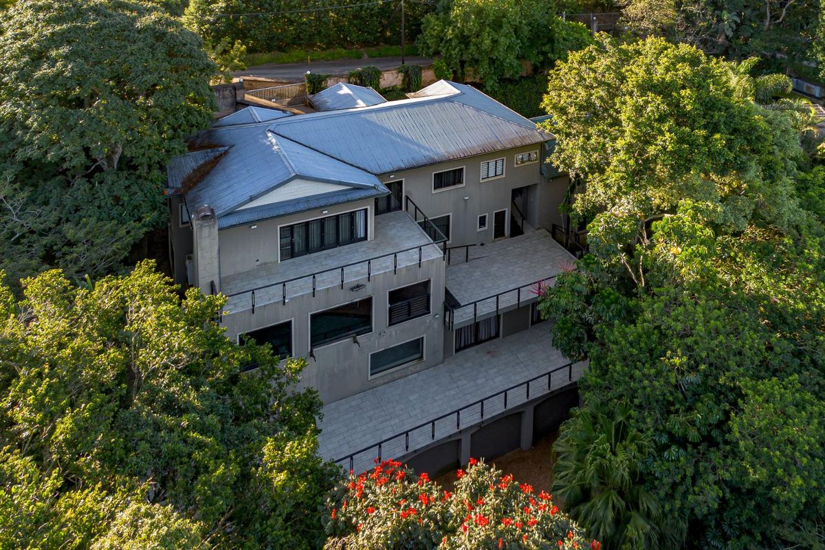 Aerial view of a multi-level guest house featuring expansive tiered balconies, metal roofing, and lush surrounding greenery.