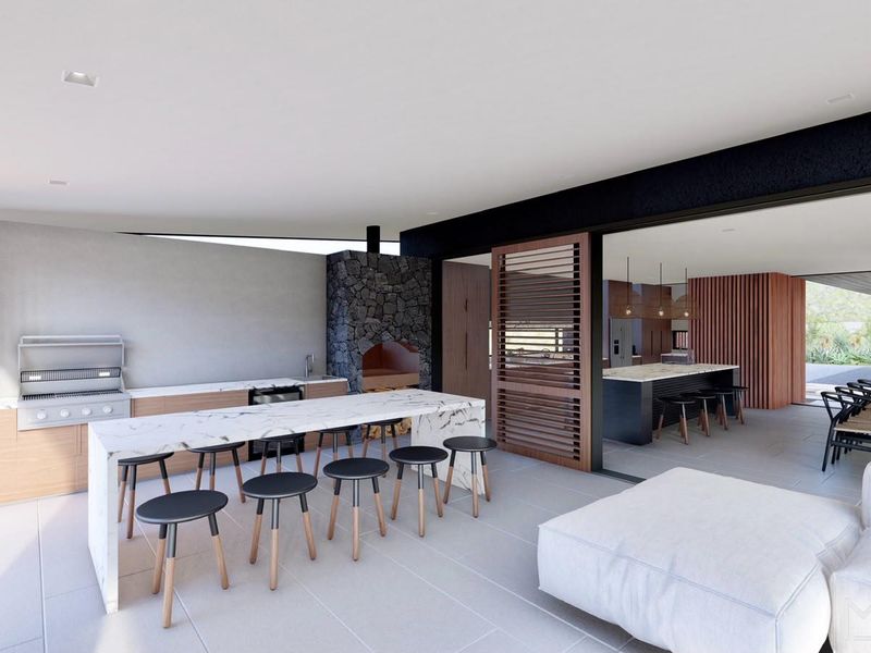 Modern covered patio featuring a built-in braai, outdoor kitchen with stone countertops, and seamless transition to the interior living space.