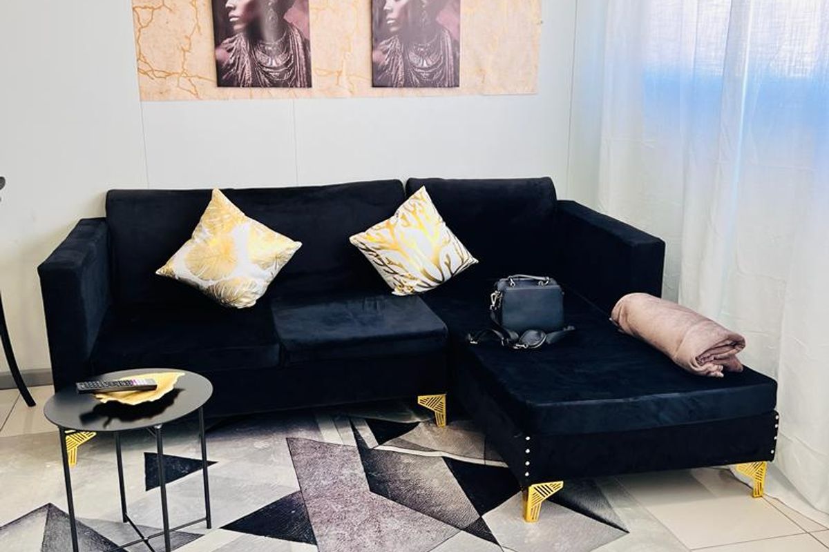 A bright living room area featuring neutral tiled flooring and window treatments, providing a clean and functional space.