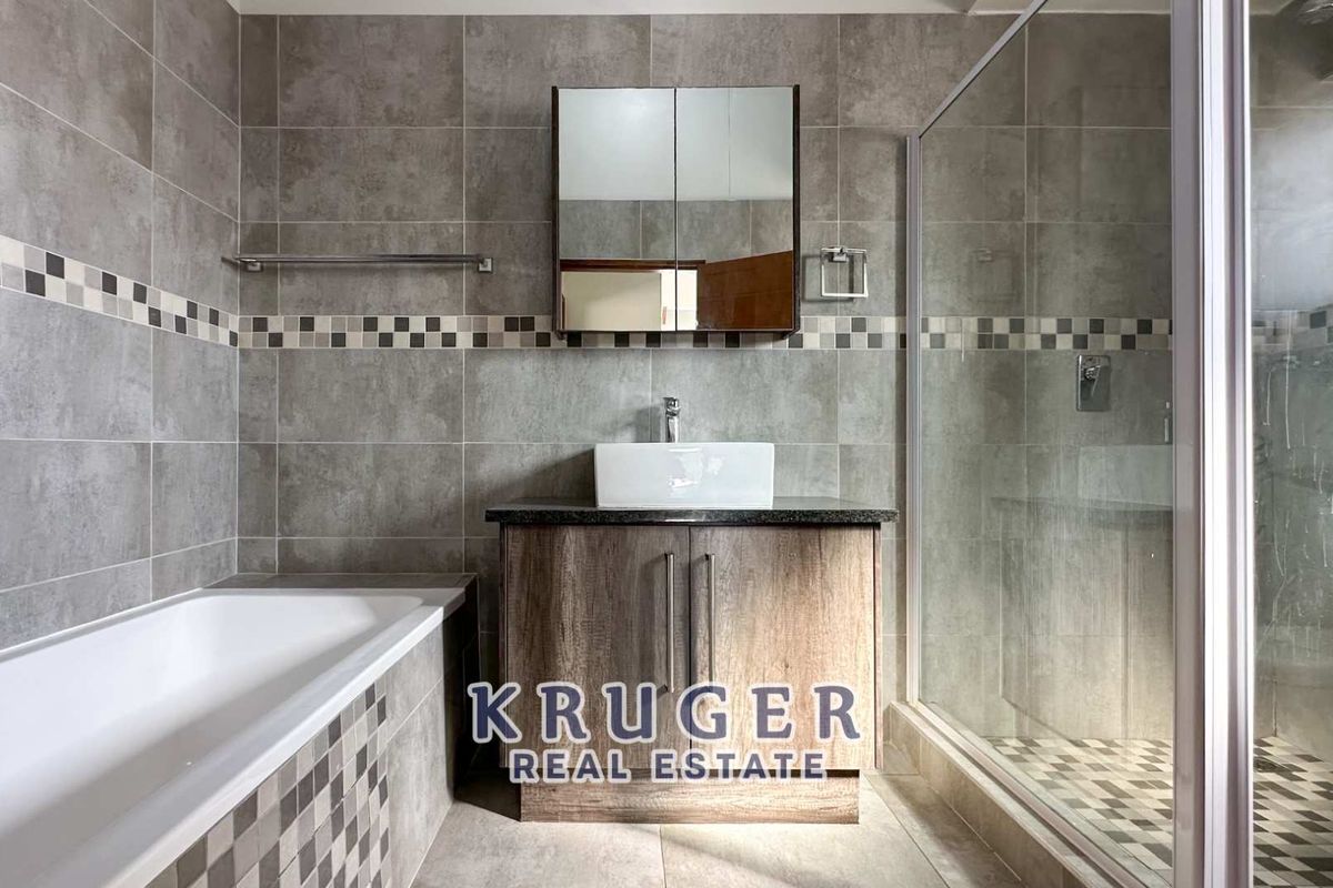 Modern bathroom featuring a separate bathtub, glass-enclosed shower, and a vanity unit with a vessel sink and mirrored cabinet.