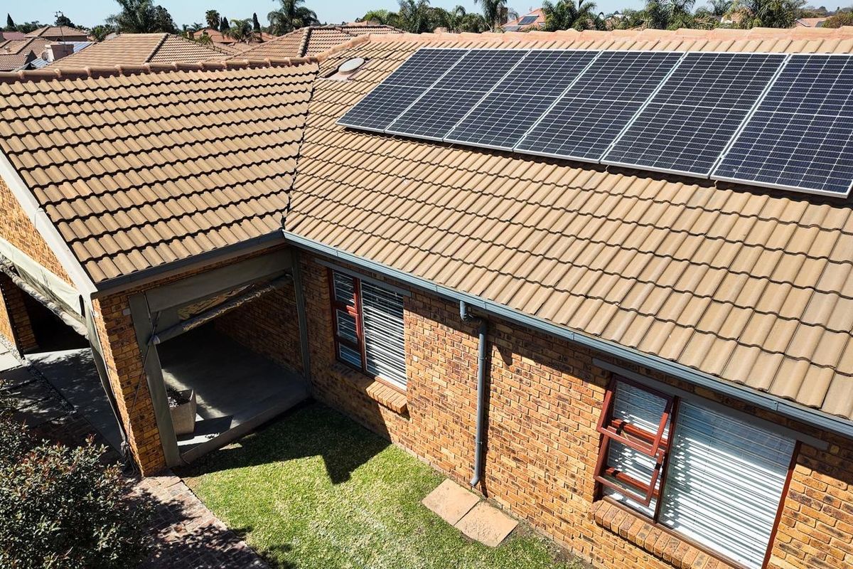 Aerial view of the townhouse roof featuring installed solar panels, brick facade, and a small private garden area.