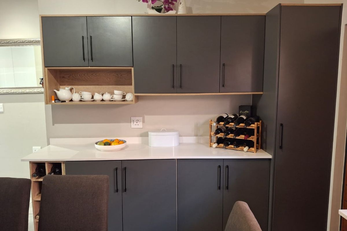 Modern kitchen cabinetry featuring dark grey matte finish doors, light wood accents, and a clean white countertop, providing ample storage and workspace.