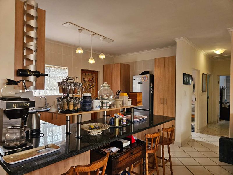 Functional kitchen featuring granite countertops, ample built-in cabinetry, and a breakfast bar, leading into a tiled hallway area.