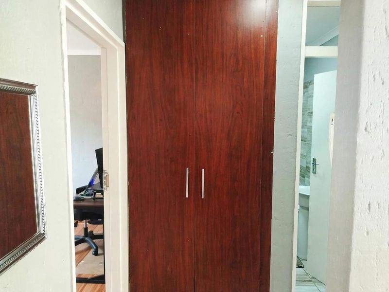 A hallway featuring a dark wood built-in cupboard with metal handles, providing storage space between adjacent rooms.