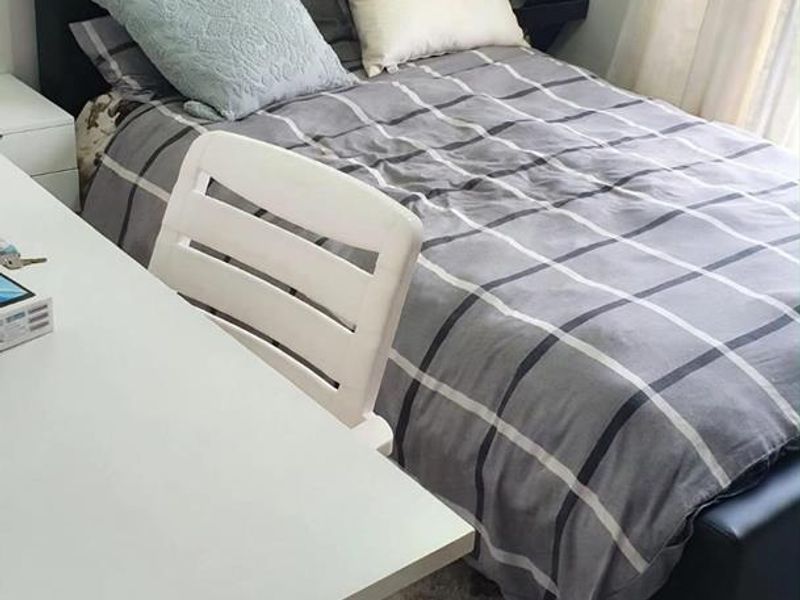 A compact bedroom featuring neutral wall finishes and tiled flooring, suitable for a guest room or home office setup.