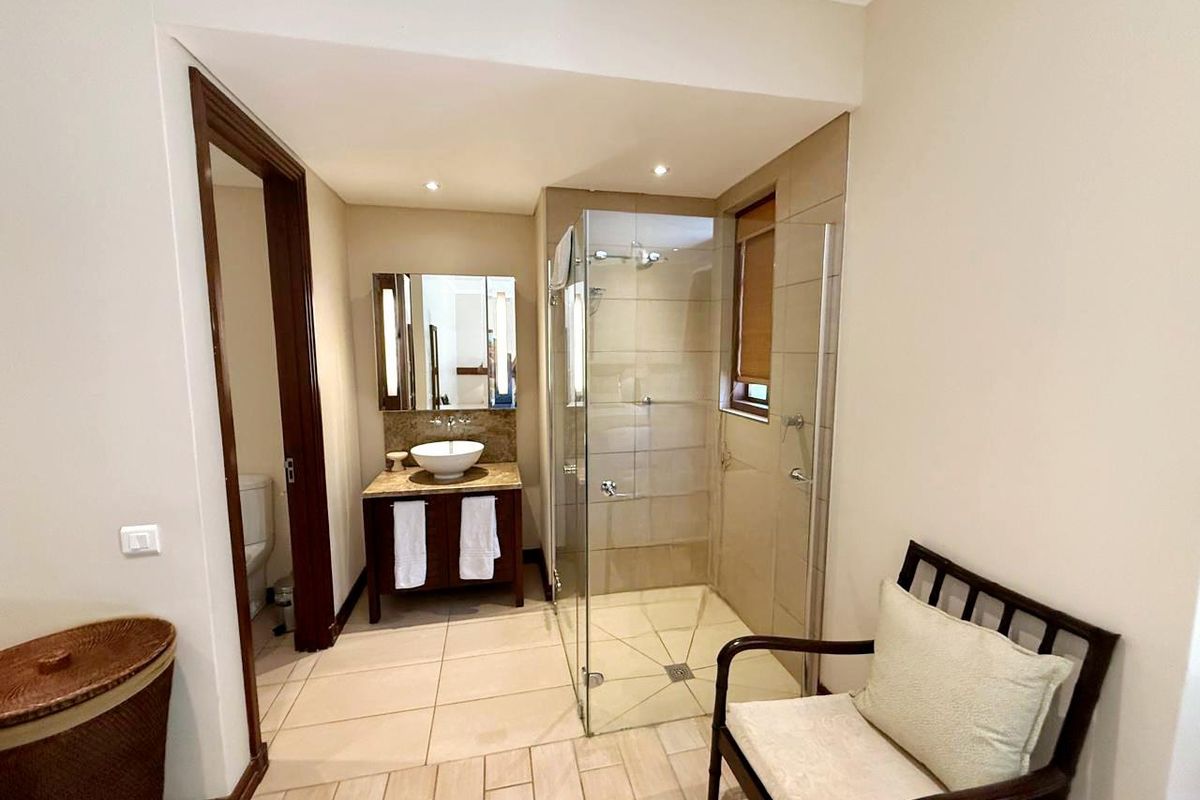 A well-maintained bathroom featuring a glass-enclosed shower, a modern vessel sink vanity, and neutral floor tiling.