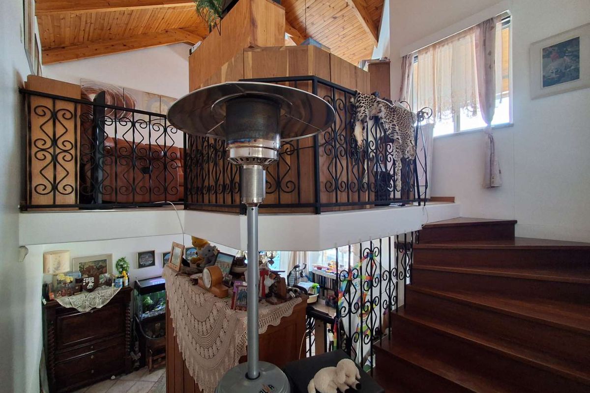 Multi-level living area featuring a timber staircase, vaulted timber-clad ceiling, and decorative wrought iron balustrades.