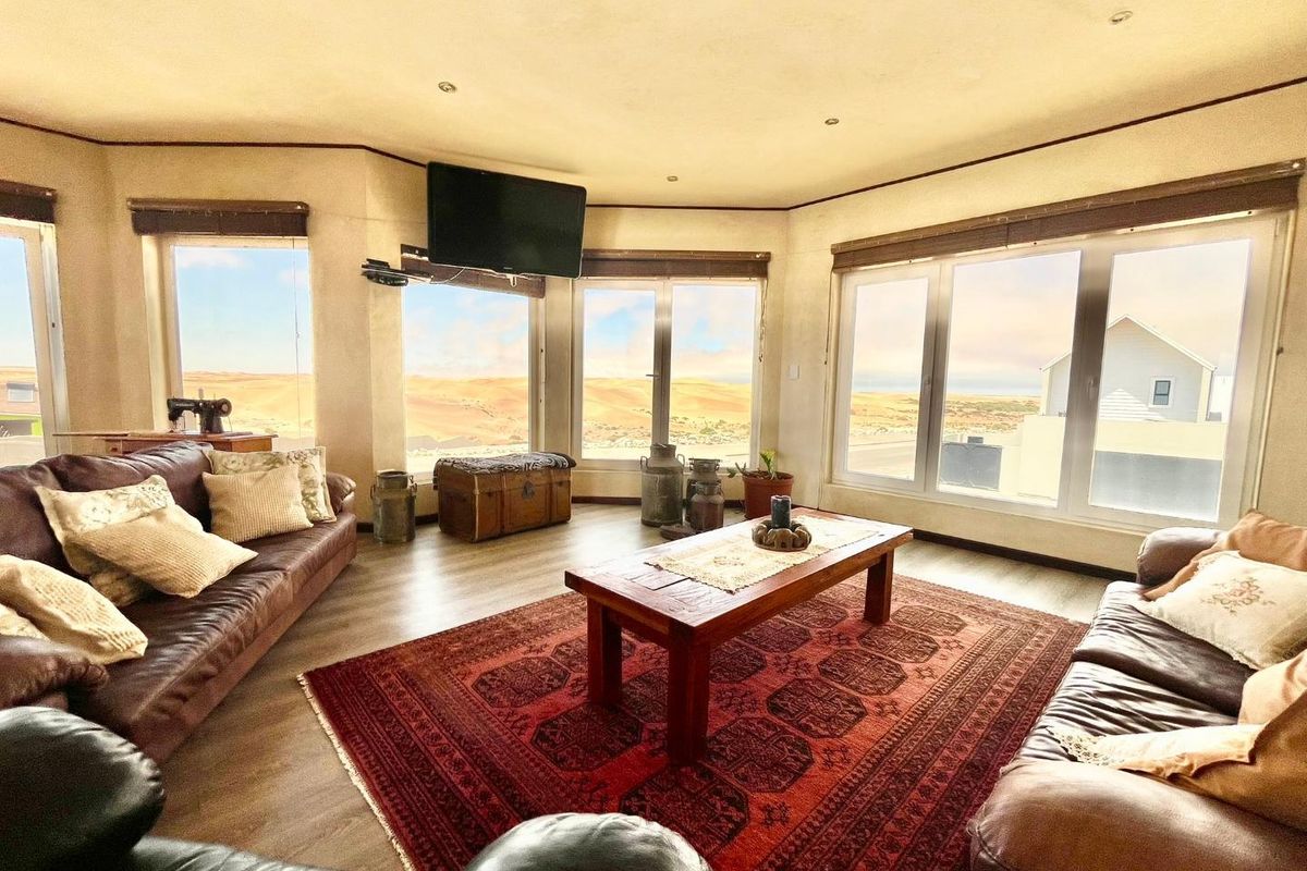Spacious living room featuring large windows with panoramic desert views, recessed ceiling lighting, and durable wood-look flooring.