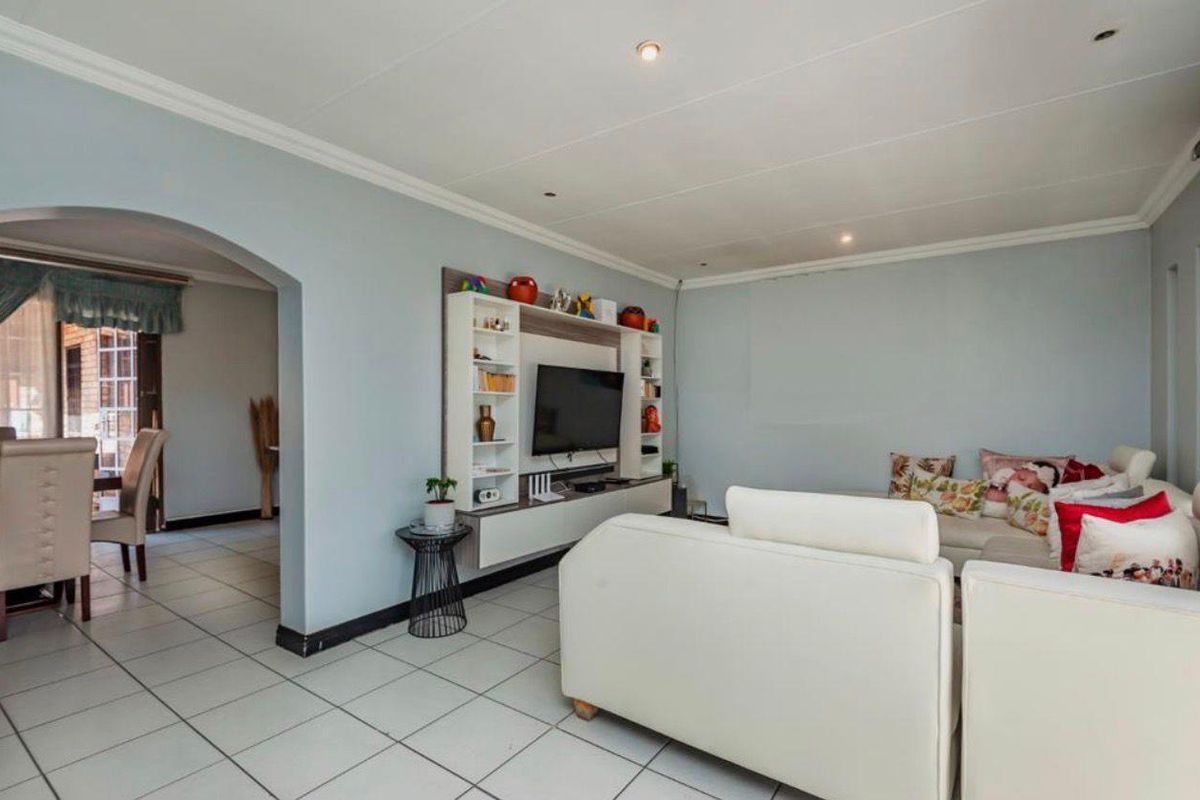 A spacious living room featuring tiled flooring, an arched entryway, and a built-in media wall unit.