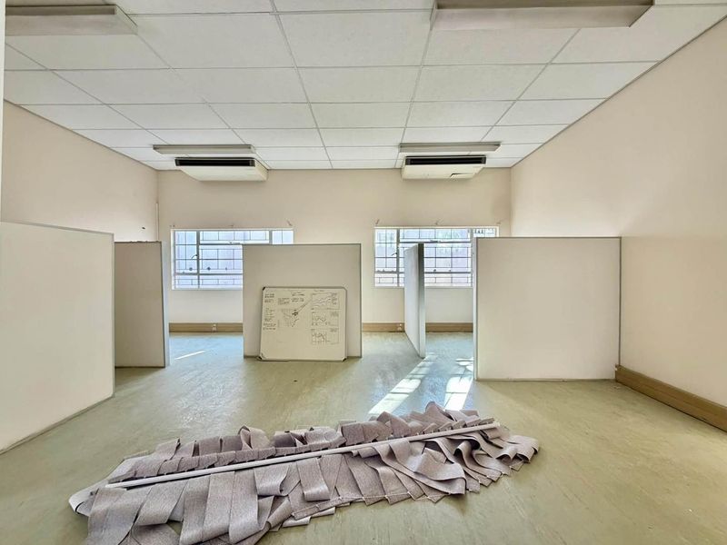 Open-plan office space featuring suspended ceilings, integrated air conditioning units, and modular partition walls, offering a functional layout for professional use.