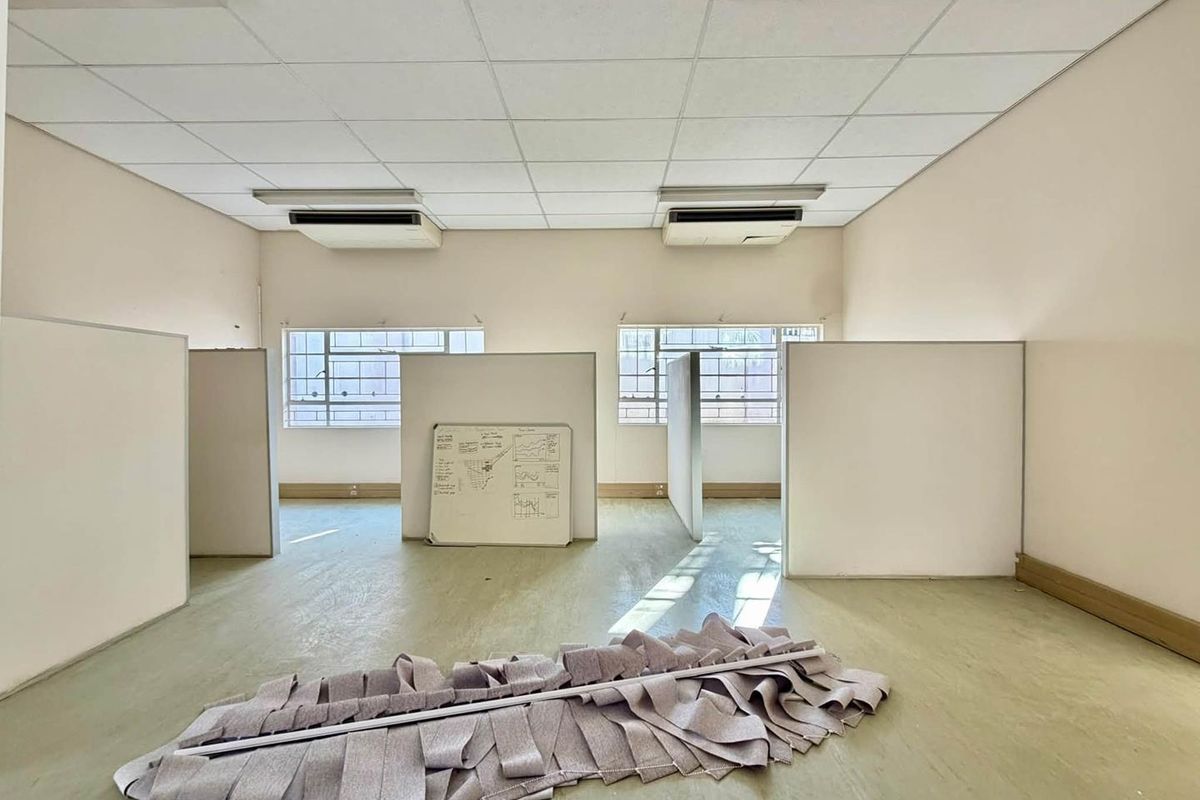 Open-plan office space featuring suspended ceilings, integrated air conditioning units, and modular partition walls, offering a functional layout for professional use.