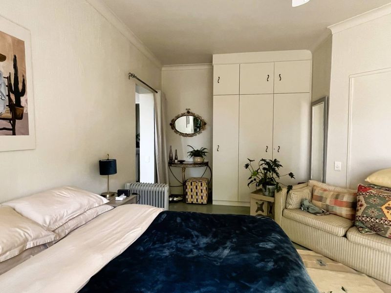 A bedroom featuring a large built-in wardrobe with ample storage space and classic cove cornice detailing.