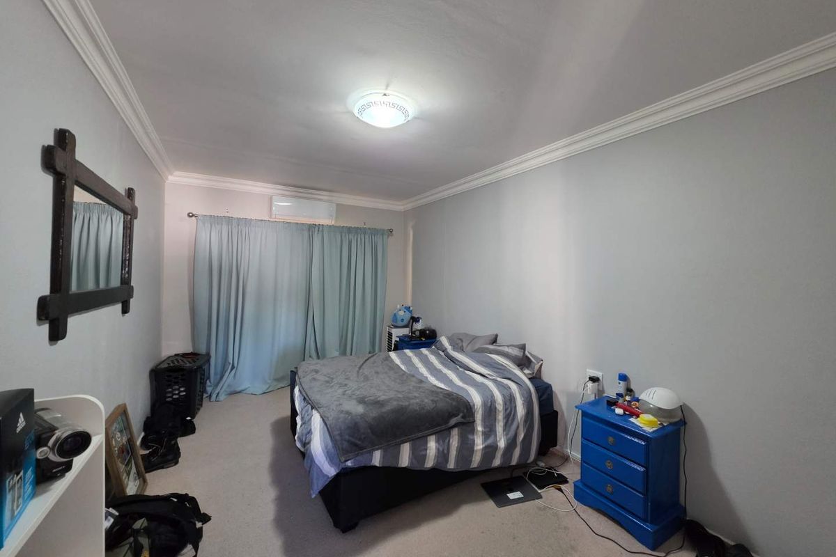 A bedroom featuring crown molding, wall-mounted air conditioning unit, and carpeted flooring.