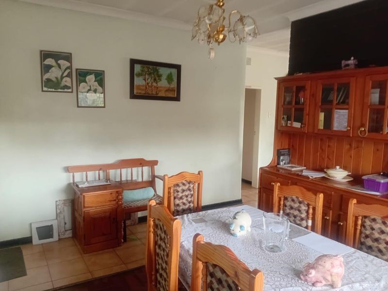 A dining room featuring tiled flooring, coved ceiling details, and a central chandelier, providing a functional space for family meals.
