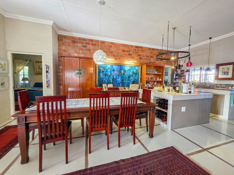 Open-plan dining and kitchen area featuring an exposed brick feature wall, central kitchen island with integrated storage, and stylish pendant lighting.