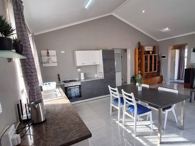 Spacious open-plan kitchen and dining area featuring modern cabinetry, tiled flooring, and a vaulted ceiling, creating a bright and functional living space.