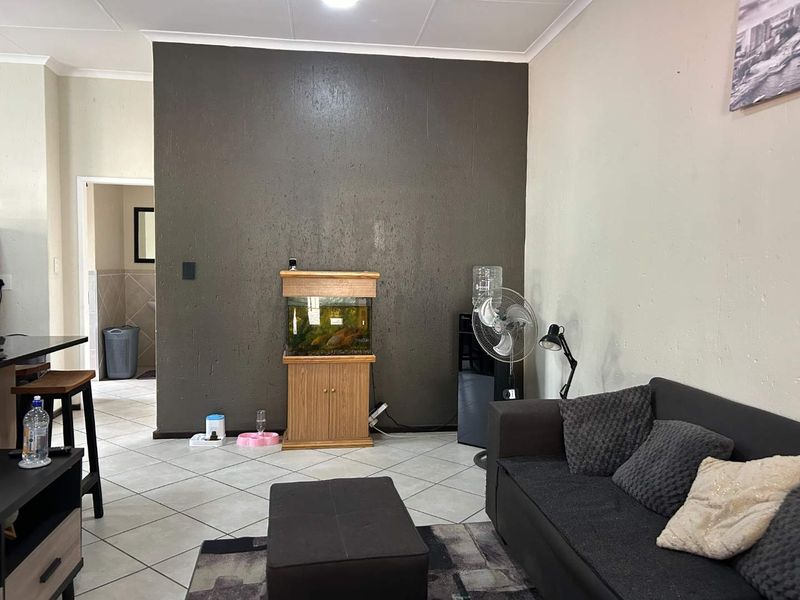 A living room area featuring tiled flooring and a dark accent wall, providing a functional space with potential for aesthetic updates.
