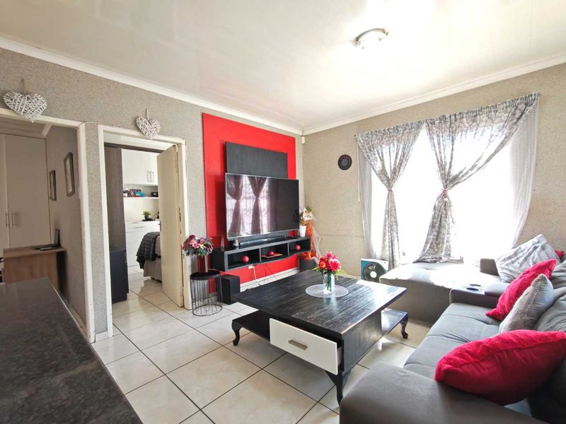 A living room featuring tiled flooring, cove cornicing, and a built-in media wall unit with a red accent panel.