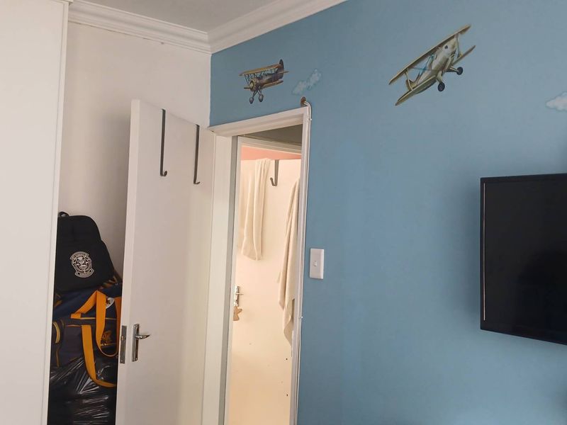 A bedroom featuring a built-in wardrobe and blue accent wall, providing a functional space with direct access to an adjacent room.