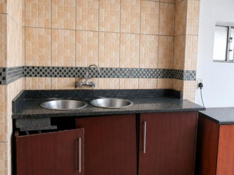 A kitchen area featuring a double bowl sink, granite countertops, and dark wood-look cabinetry with visible damage to one of the cabinet doors.