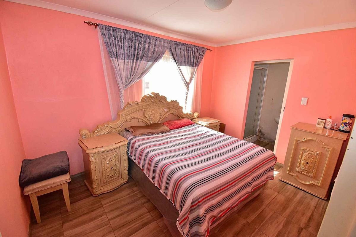 A bedroom featuring wood-look tiled flooring and an en-suite bathroom access point.