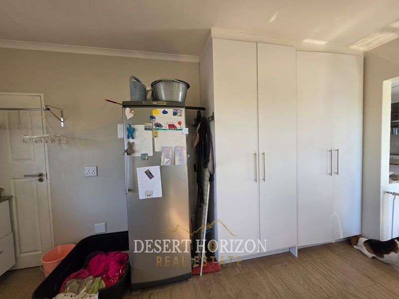 A functional laundry area featuring built-in white cabinetry and laminate flooring, providing practical storage space for household utility needs.