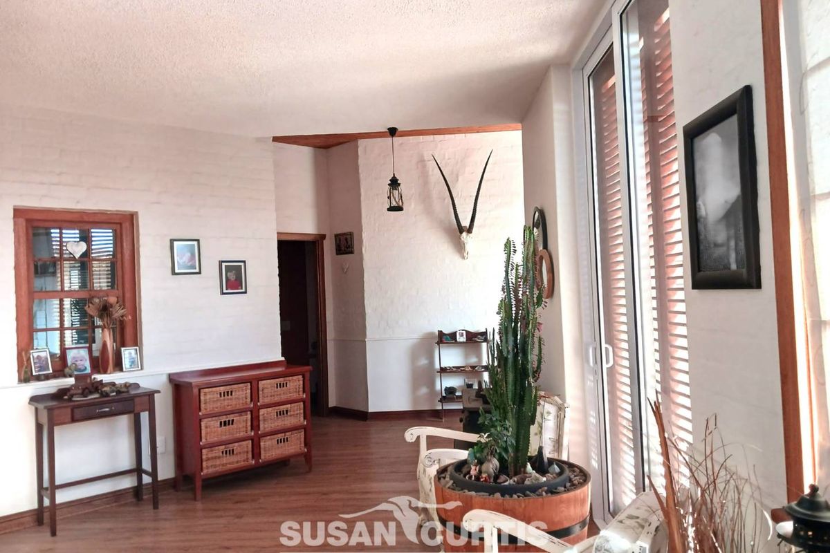 A bright living area featuring white painted brick walls, timber-framed windows, and large sliding glass doors leading to the exterior.