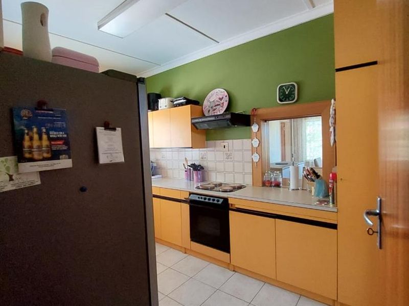 A functional kitchen featuring built-in cabinetry, tiled flooring, and a tiled backsplash, offering a practical layout for daily meal preparation.