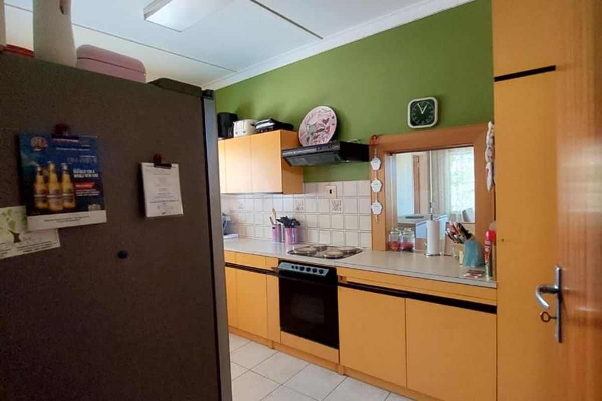 A functional kitchen featuring built-in cabinetry, tiled flooring, and a tiled backsplash, offering a practical layout for daily meal preparation.